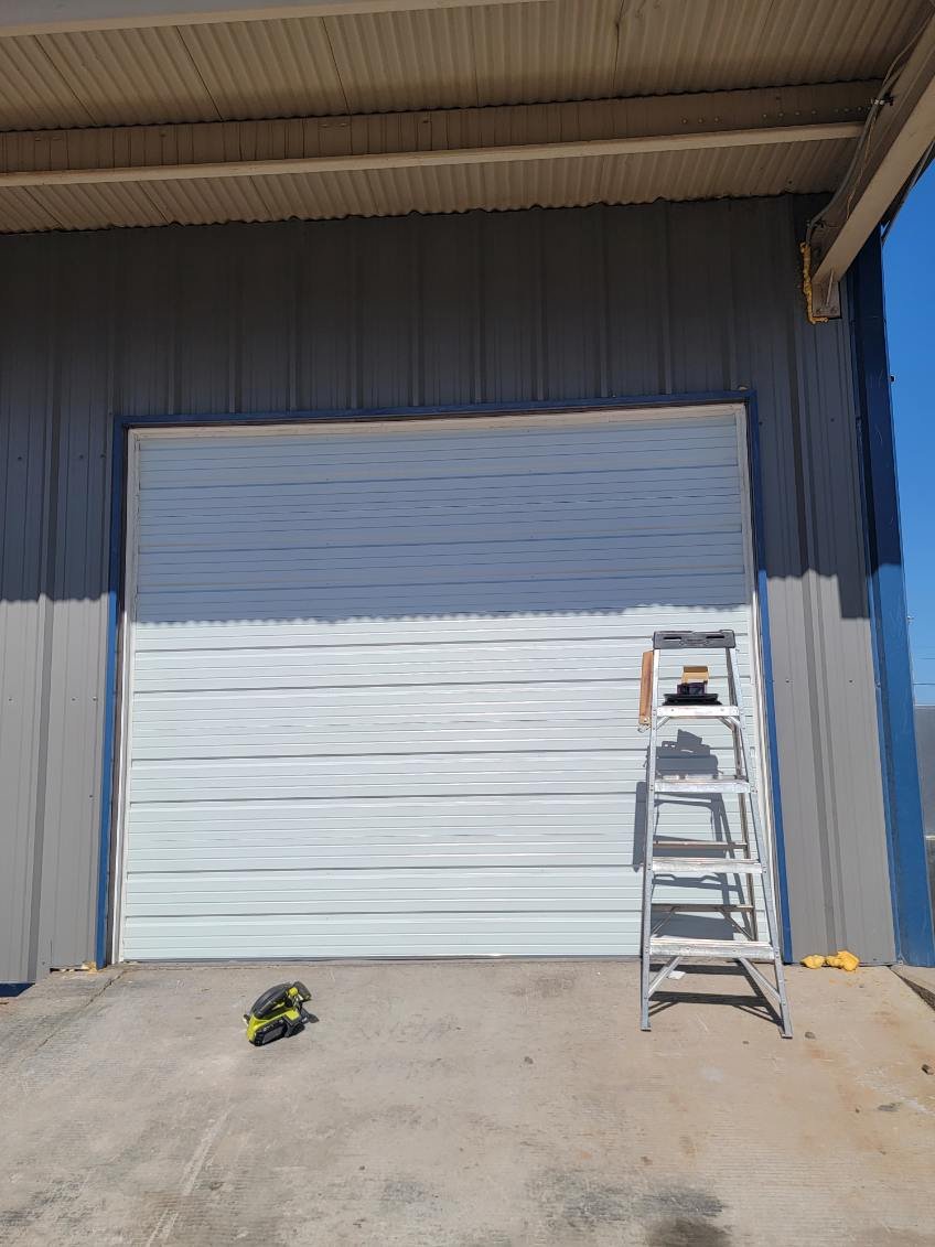 Large roll-up door in a metal building with a ladder positioned for service access
