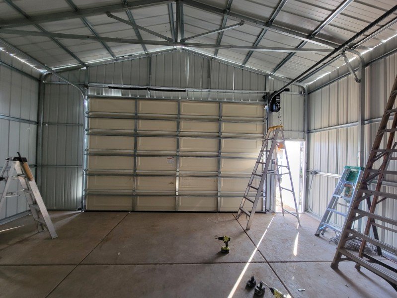 Interior view of a large roll-up garage door system with tracks and service ladders
