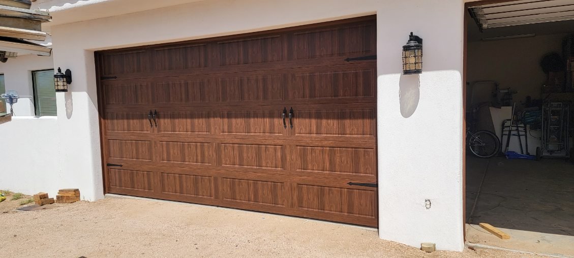Wood-look residential garage door with decorative handles and window panels